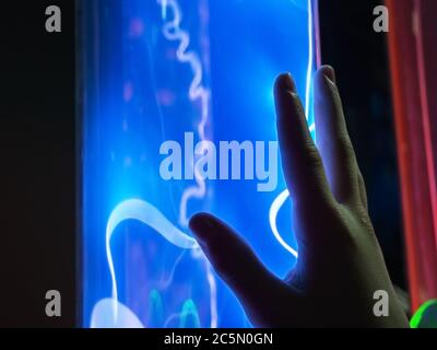 Nahaufnahme einer Hand, die nach einer Flasche mit elektrischen Entladungen im Inneren greift Stockfoto