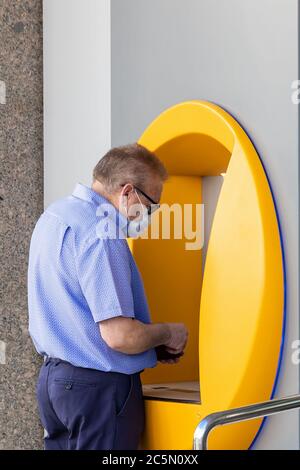 Punta Umbria, Huelva, Spanien - 3. Juni 2020: Senior Mann mit Bankkreditkarte in Geldautomaten trägt eine Schutzmaske wegen covid-19 coronav Stockfoto