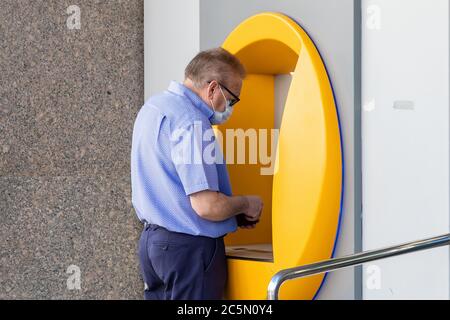 Punta Umbria, Huelva, Spanien - 3. Juni 2020: Senior Mann mit Bankkreditkarte in Geldautomaten trägt eine Schutzmaske wegen covid-19 coronav Stockfoto