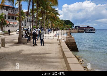 Stone Town Sansibar, Tansania - 7. Oktober 2019: Menschen, die entlang der Strandpromenade von Stone Town spazieren. Tansania, Afrika Stockfoto