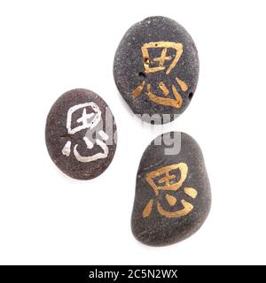 Chinesisches Zeichen xi oder japanisches Iki, was Ruhe bedeutet, geschrieben auf einem Kieselstein, isoliert auf weiß Stockfoto