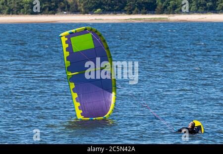 Ein Mann ist auf seinem Board bereit für seinen Drachen zu fliegen, um Kite Boarding in der Bucht zu starten. Stockfoto