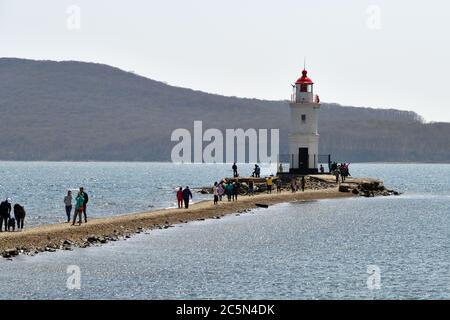 Wladiwostok, Russland - 28. April 2019: Menschen besuchen weißen Leuchtturm mit rotem Dach auf Tokarev Katze. Bosporus Eastern. Region Primorski Stockfoto