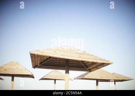 Hölzerne Strandüberdachen auf blauem Himmel Hintergrund. Stockfoto