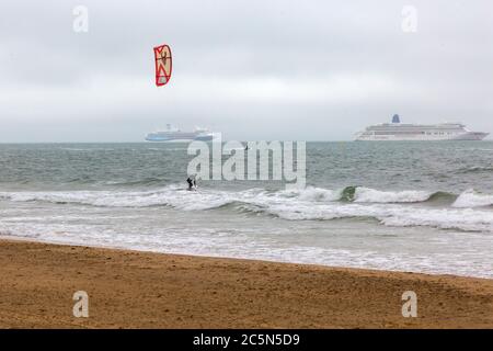 Bournemouth, Dorset, Großbritannien. Juli 2020. Wetter in Großbritannien: Kitesurfer nutzen die windigen Bedingungen und Wellen an einem windigen, niesigen und trüben Morgen an den Stränden von Bournemouth mit Marella Explorer Kreuzfahrtschiff und Aurora Kreuzfahrtschiffen in der Ferne. Kitesurfer Kitesurfer Kitesurfer Kitesurfer Kitesurfer Kitesurfen Kitesurfen Kitesurfen Kitesurfen Kitesurfen Credit: Carolyn Jenkins/Alamy Live News Stockfoto