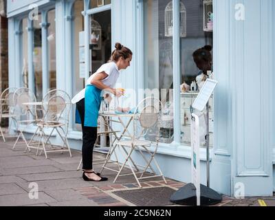 Rochester, Kent, Großbritannien. Juli 2020. Eine Kellnerin putzt einen Tisch vor einem Café auf der Rochester High Street. Die Vereinigten Staaten eröffnen am 4. Juli Pubs, Restaurants, Barbiere, Friseure und Hotels wieder, nachdem sie seit März wegen des Coronavirus-Ausbruchs geschlossen sind. Kredit: Yousef Al Nasser/ Alamy Live Nachrichten Stockfoto