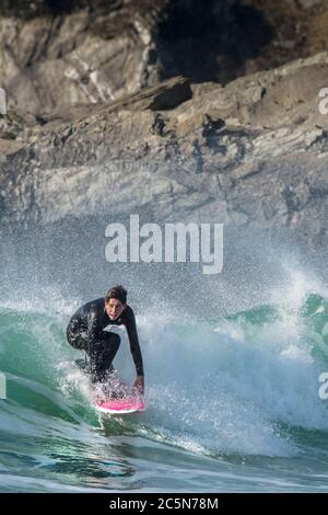 Ein junger Surfer, der auf einer Welle bei Fistral in Newquay in Cornwall reitet. Stockfoto