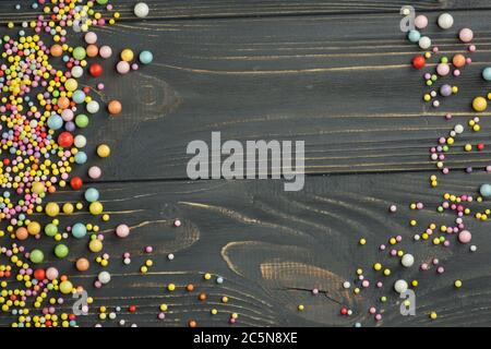 Bunte Schaumstoffkugel Textur. Buntes Polystyrol-Schaumstoff auf schwarzem Holzhintergrund Stockfoto