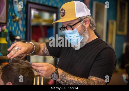 Friseur schneidet Haare tragen PPE Gesichtsmaske im Friseursalon in den ersten Tagen der Lockdown während Coronavirus Pandemie. England Juli 2020 Stockfoto