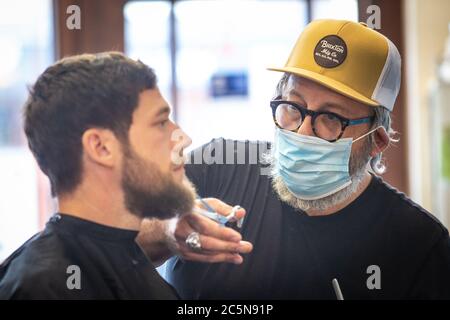Friseur schneidet Haare tragen PPE Gesichtsmaske im Friseursalon in den ersten Tagen der Lockdown während Coronavirus Pandemie. England Juli 2020 Stockfoto