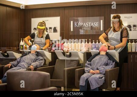 Friseure in PSA Gesichtsvisoren waschen die Haare von zwei Kunden in Gesichtsmasken während der ersten Tage der Lockdown Lockerung in England während der Covid Pandemie Stockfoto