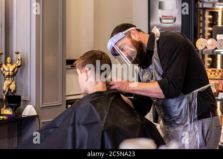 Harrogate, North Yorkshire, Großbritannien. Juli 2020. Hugo Wragg vom Barbiergeschäft Steca N.6, bei der Arbeit mit voller PSA, während die Barbiere am Super-Samstag wieder für die Öffentlichkeit geöffnet werden. Kredit: ernesto rogata/Alamy Live Nachrichten Stockfoto