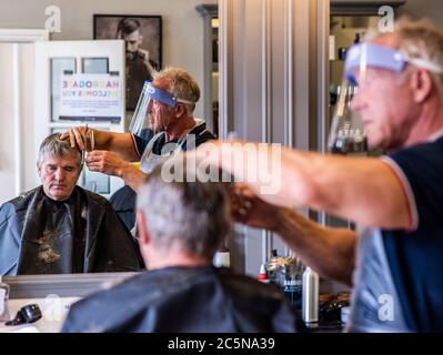 Harrogate, North Yorkshire, Großbritannien. Juli 2020. David Steca, Eigentümer des Barbiers Steca N.6, ist bei der Arbeit und trägt vollständige PSA, während die Barbiere am Super-Samstag wieder für die Öffentlichkeit zugänglich sind. Kredit: ernesto rogata/Alamy Live Nachrichten Stockfoto