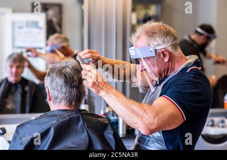 Harrogate, North Yorkshire, Großbritannien. Juli 2020. David Steca, Eigentümer des Barbiers Steca N.6, ist bei der Arbeit und trägt vollständige PSA, während die Barbiere am Super-Samstag wieder für die Öffentlichkeit zugänglich sind. Kredit: ernesto rogata/Alamy Live Nachrichten Stockfoto