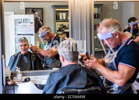 Harrogate, North Yorkshire, Großbritannien. Juli 2020. David Steca, Eigentümer des Barbiers Steca N.6, ist bei der Arbeit und trägt vollständige PSA, während die Barbiere am Super-Samstag wieder für die Öffentlichkeit zugänglich sind. Kredit: ernesto rogata/Alamy Live Nachrichten Stockfoto