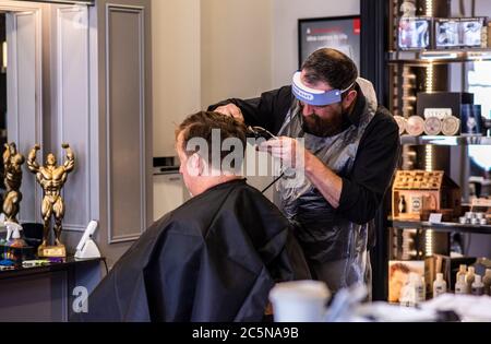 Harrogate, North Yorkshire, Großbritannien. Juli 2020. Hugo Wragg vom Barbiergeschäft Steca N.6, bei der Arbeit mit voller PSA, während die Barbiere am Super-Samstag wieder für die Öffentlichkeit geöffnet werden. Kredit: ernesto rogata/Alamy Live Nachrichten Stockfoto