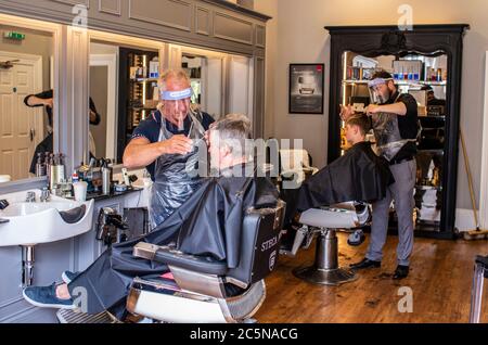 Harrogate, North Yorkshire, Großbritannien. Juli 2020. David Steca und Hugo Wragg vom Steca N.6 Friseurladen, bei der Arbeit mit voller PSA, während die Barbiere am Super Saturday wieder für die Öffentlichkeit geöffnet werden. Kredit: ernesto rogata/Alamy Live Nachrichten Stockfoto