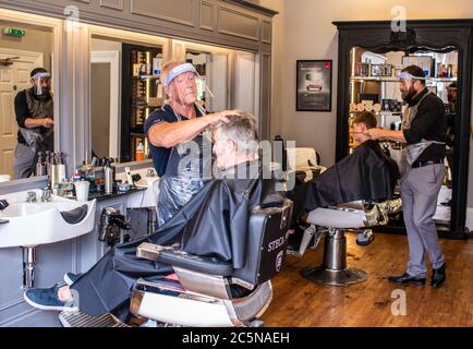 Harrogate, North Yorkshire, Großbritannien. Juli 2020. David Steca und Hugo Wragg vom Steca N.6 Friseurladen, bei der Arbeit mit voller PSA, während die Barbiere am Super Saturday wieder für die Öffentlichkeit geöffnet werden. Kredit: ernesto rogata/Alamy Live Nachrichten Stockfoto