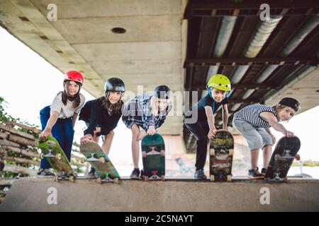 Extremsport in der Stadt. Skateboarding Club für Kinder. Gruppenfreunde posieren auf Rampe im Skatepark. Frühe Jugend im Skate-Training. Freunde Stockfoto