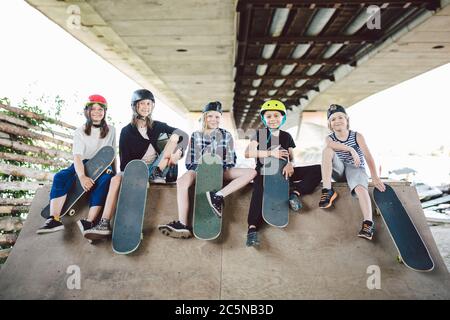 Extremsport in der Stadt. Skateboarding Club für Kinder. Gruppenfreunde posieren auf Rampe im Skatepark. Frühe Jugend im Skate-Training. Freunde Stockfoto