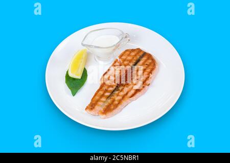 Gegrillter Lachs mit Kaviar, Zitrone und Sahne-Sauce auf blauem Hintergrund isoliert Stockfoto