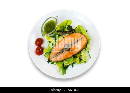 Gegrilltes Lachssteak auf Salat mit Kirschtomaten und grüner Sauce auf weiß isoliert Stockfoto