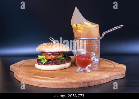 Frisch leckere Burger und Bratkartoffeln mit roter Sauce auf einem Holzbrett im Restaurant Stockfoto