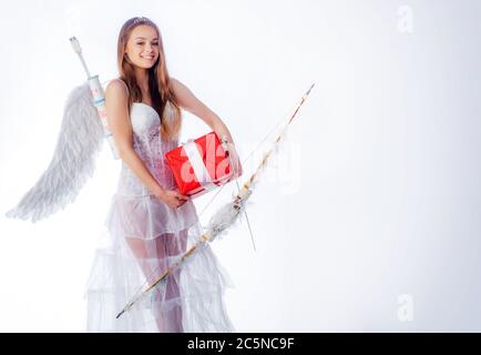 Niedliche kleine weibliche Amor schießt einen Bogen. Pfeil der Liebe. Kleine Göttin mit weißen Flügeln allein auf blauem Himmel Hintergrund. Teen Angel. Nettes Teenager Mädchen. Engel Stockfoto