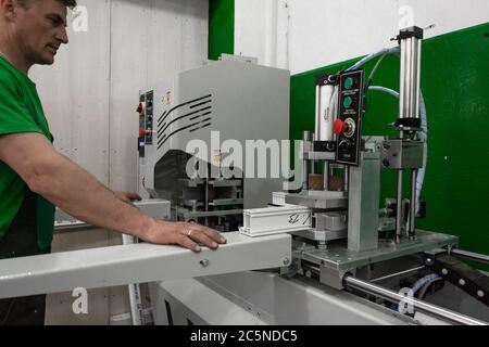 Arbeiter an einer Maschine zum Schweißen von Fenstern und Türen aus PVC. Fabrik für die Produktion von Aluminium und PVC-Fenstern und Türen. Stockfoto