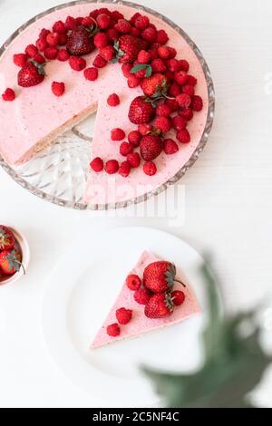 Köstliche frische Torte mit zarter Sahne, Himbeeren, Erdbeeren auf einem weißen Tisch. Vertikales Foto Stockfoto