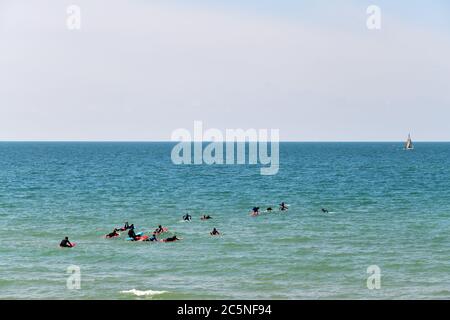 Tel Aviv, Israel - 5. April 2019: Undefinierte Surfer mit Surfbrettern im Wasser des Mittelmeers. Geula Strand Stockfoto