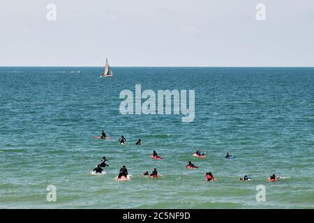 Tel Aviv, Israel - 5. April 2019: Undefinierte Surfer mit Surfbrettern im Wasser des Mittelmeers. Geula Strand Stockfoto