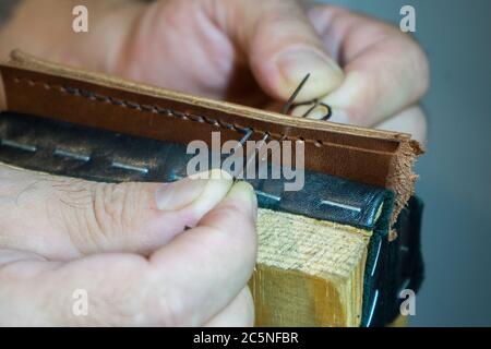 Herrenhände sind mit einer Handnaht groß aus Leder genäht. Stockfoto