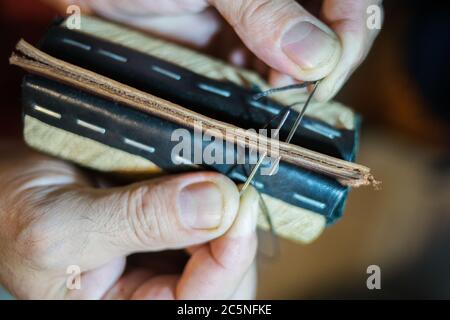 Herrenhände sind mit einer Handnaht groß aus Leder genäht. Stockfoto