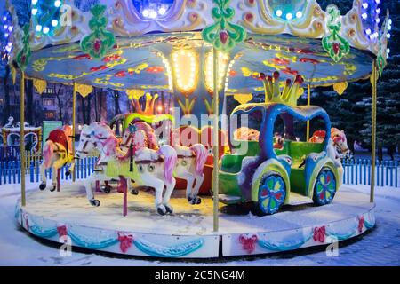 Das Kinderkarussell leuchtet im Winter wunderschön. Attraktion für Kinder Stockfoto