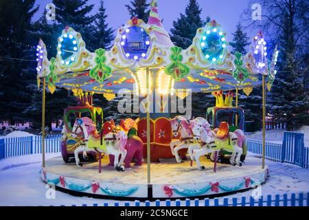 Das Kinderkarussell leuchtet im Winter wunderschön. Attraktion für Kinder Stockfoto