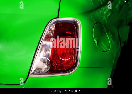 Rücklicht-Bremsleuchte eines Eco-Elektroautos in grüner Nahaufnahme der Fahrzeugrückseite. Stockfoto