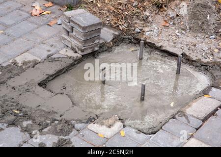 Verstärkung, die unter dem Beton heraussteht, Nahaufnahme des Fundaments und quadratische Pflasterplatten. Stockfoto