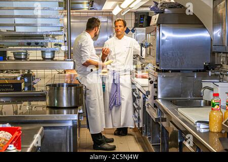 Der mit einem Michelin-Stern ausgezeichnete Koch Thomas Kellermann spricht mit seinem Souschef Robert Morgan in der Küche des Schlosses Wernberg, Wernberg-Köblitz, Oberpfalz, Deutschland. Stockfoto