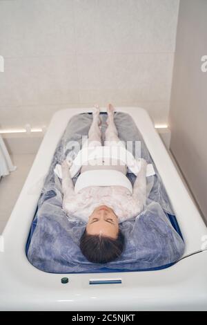 Ruhige junge Frau genießen schwimmende Verfahren in Schönheitssalon Stockfoto