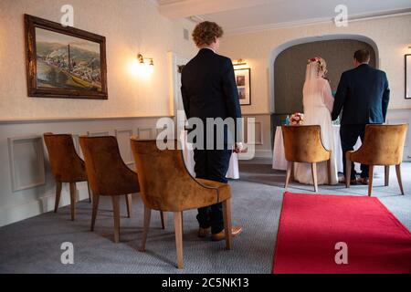 Tracie Kenny und Neal Arden bei ihrer Hochzeitszeremonie im Best Western Valley Hotel, Ironbridge, wie Neals Sohn Callum zuschaut, wie Hochzeiten in England wieder stattfinden dürfen, mit einer maximalen Anzahl von 30 Gästen. Stockfoto