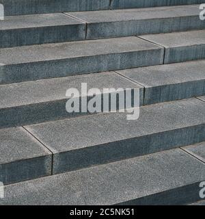 Nahaufnahme der Außenansicht einer alten Steintreppe. Muster langer grauer Stufen. Geometrisches Bild mit schrägen Linien. Abstrakte Architektur Stockfoto