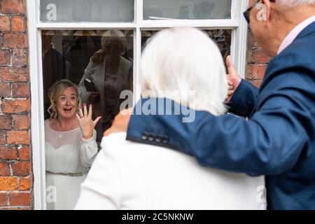 Tracie Kenny zeigt ihren Eltern ihren Ehering, Die wegen sozialer Distanzierungsmaßnahmen ihre Hochzeit mit Neal Arden von außen beobachten musste, im Best Western Valley Hotel, Ironbridge, da in England wieder Hochzeiten mit einer Höchstzahl von 30 Gästen stattfinden dürfen. Stockfoto