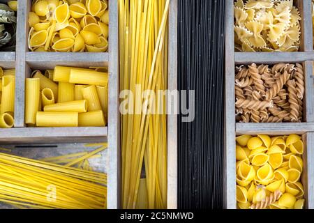 Auswahl an Pasta in einer Holzkiste mit Zellen für verschiedene Arten von Produkten Draufsicht auf die traditionelle italienische Küche. Stockfoto