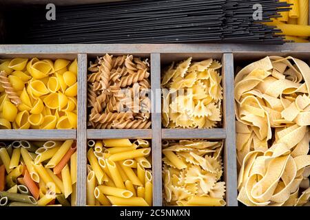 Pasta-Sortiment in Holzkastenzellen, Draufsicht auf rohe unvorbereitete Zutaten zum Kochen von Pasta. Stockfoto