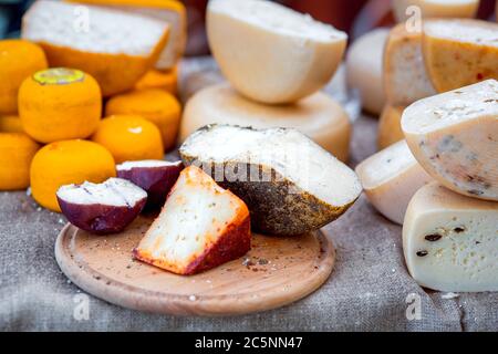 Hartkäse mit scharfer Paprika auf einem runden Holzbrett, auf einem Sacktuch geschnitten. Stockfoto