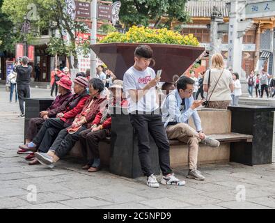 Junge und Alte teilen sich einen Sitzbereich in einer Altstadt in der Provence Yunnan im Südwesten Chinas. Stockfoto