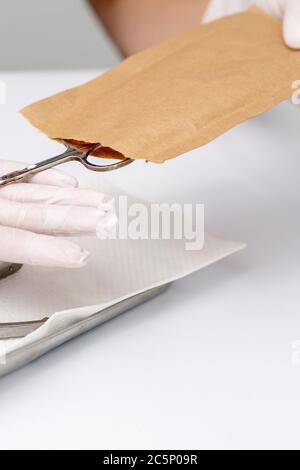 Manikuristen Hände nehmen Maniküre Werkzeuge aus Handwerk Umschlag vor Maniküre Verfahren durch den weißen Tisch Stockfoto