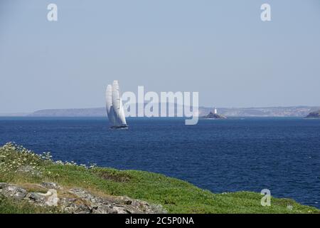 Super Yacht mit 'Soft Wing' Segeln unterwegs in St Ives Bay Blue Sea Headland im Hintergrund Hellblauer Himmel Godrevy Leuchtturm in der Ferne Stockfoto