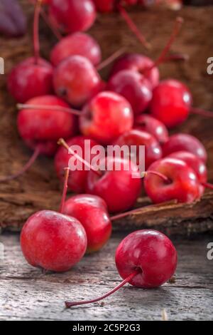 Kleine wilde und gesunde Bio-Äpfel auf einem alten Holztisch. Reife süße Äpfel in einem Korb. Komposition im Vintage-Stil. Stockfoto